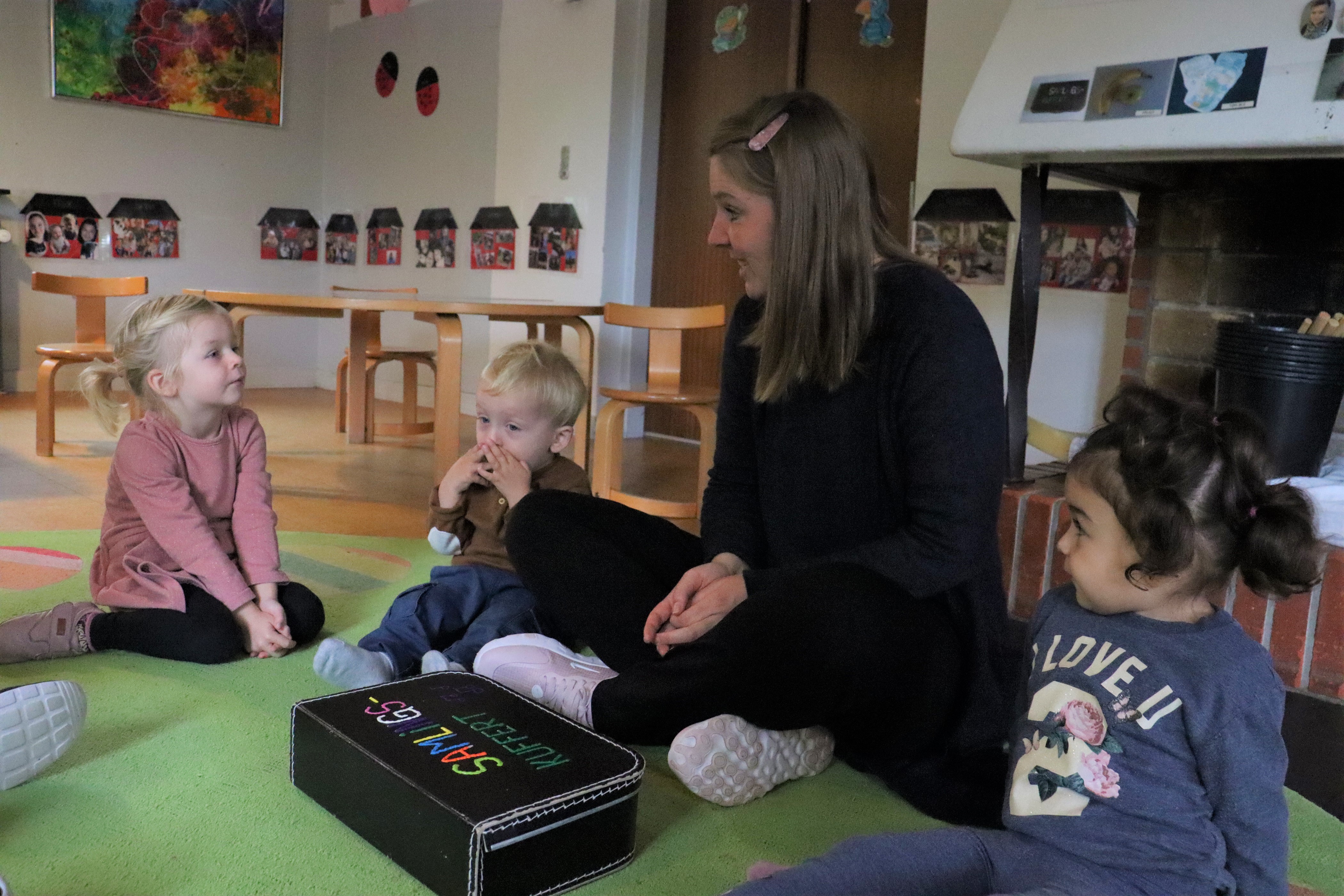 Samling i vuggestuen, hvor pædagog sidder og forklare til børnene